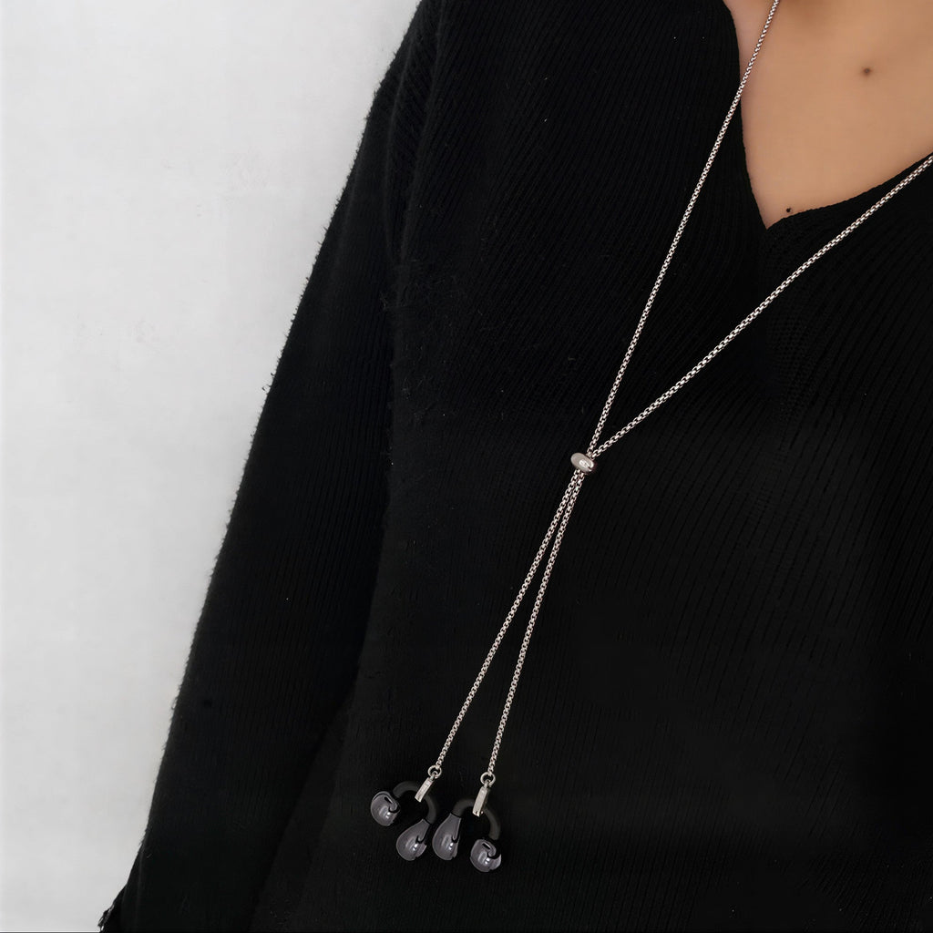 Long necklace with pendant on a person wearing a black outfit against a white background